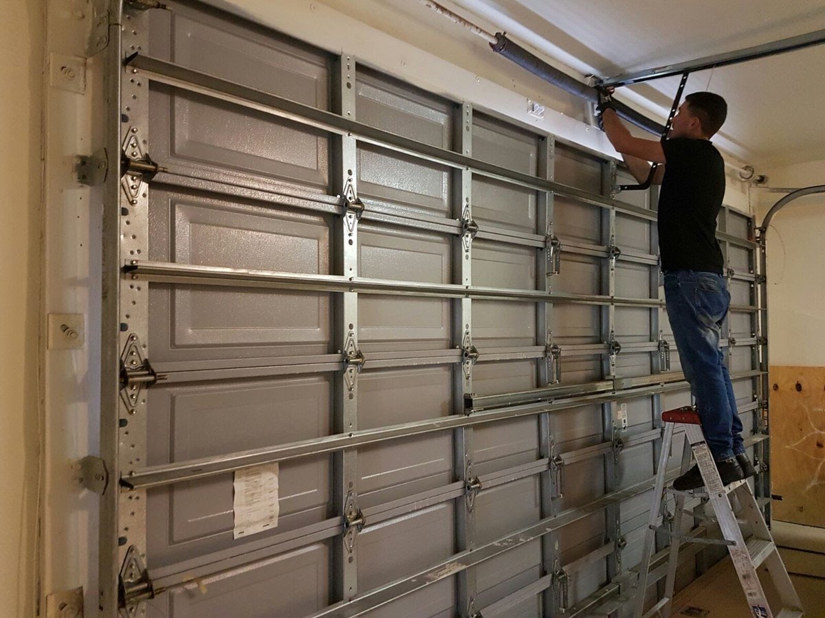 Técnico de OM Garage Door Florida reemplazando un resorte de torsión en una puerta de garaje en el condado de Broward